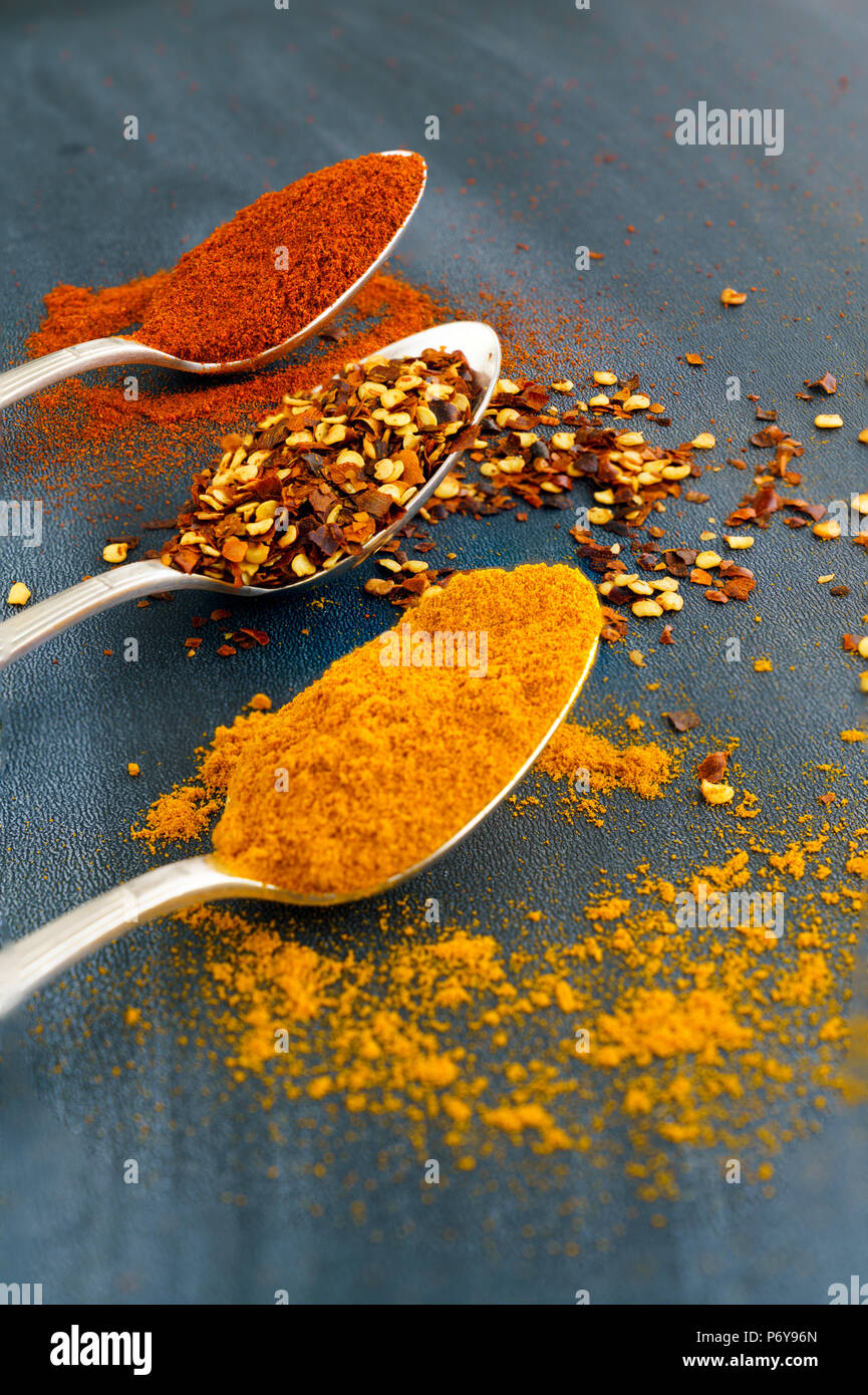 Argento Vintage cucchiai colmi di paprika, curcuma e peperoncino in scaglie su sfondo scuro Foto Stock