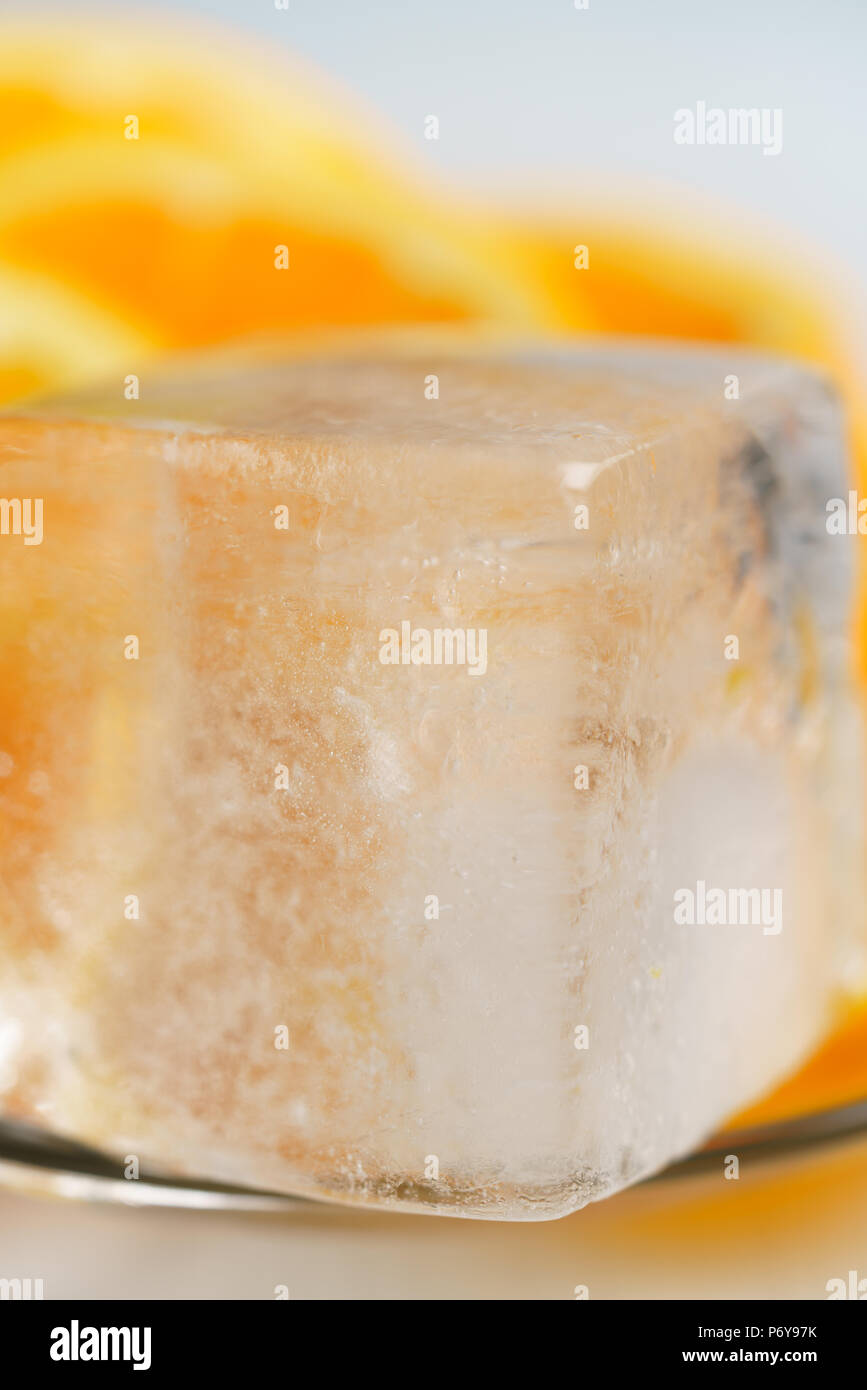 Il cubo di ghiaccio con fettine di arancia su una lastra di vetro. Macro shot, ad alta risoluzione Foto Stock