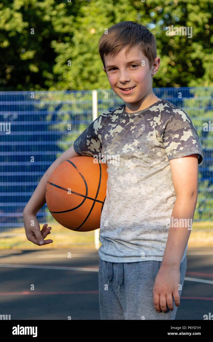 Ragazzo adolescente seduto su una palla da basket su una corte cercando  triste Foto stock - Alamy