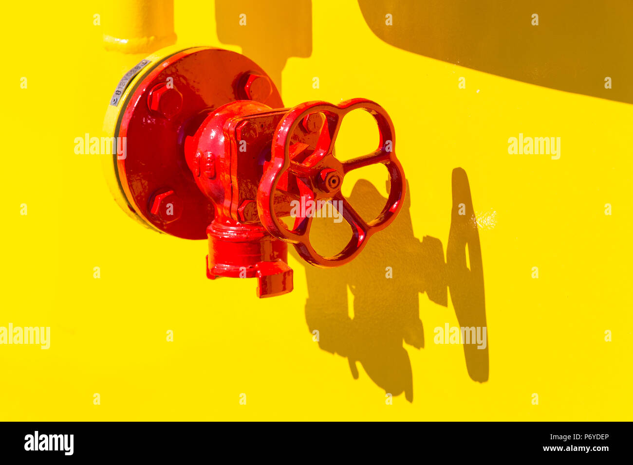 La vibrante maniglia rossa in condizioni di luce solare intensa su sfondo giallo Foto Stock