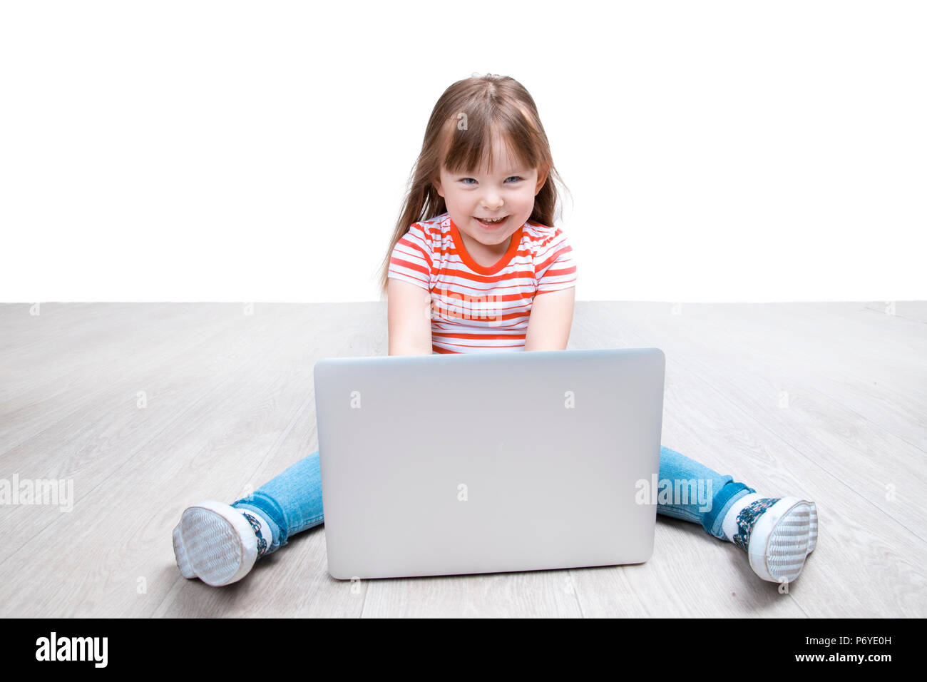 Bambina è seduta sul pavimento con il suo computer portatile Foto Stock