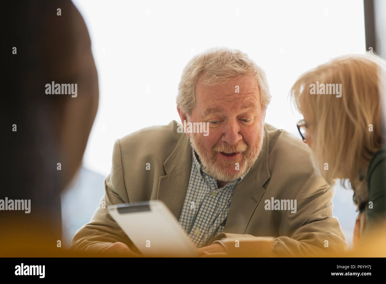 Senior business persone utilizzando la tavoletta digitale in riunione Foto Stock