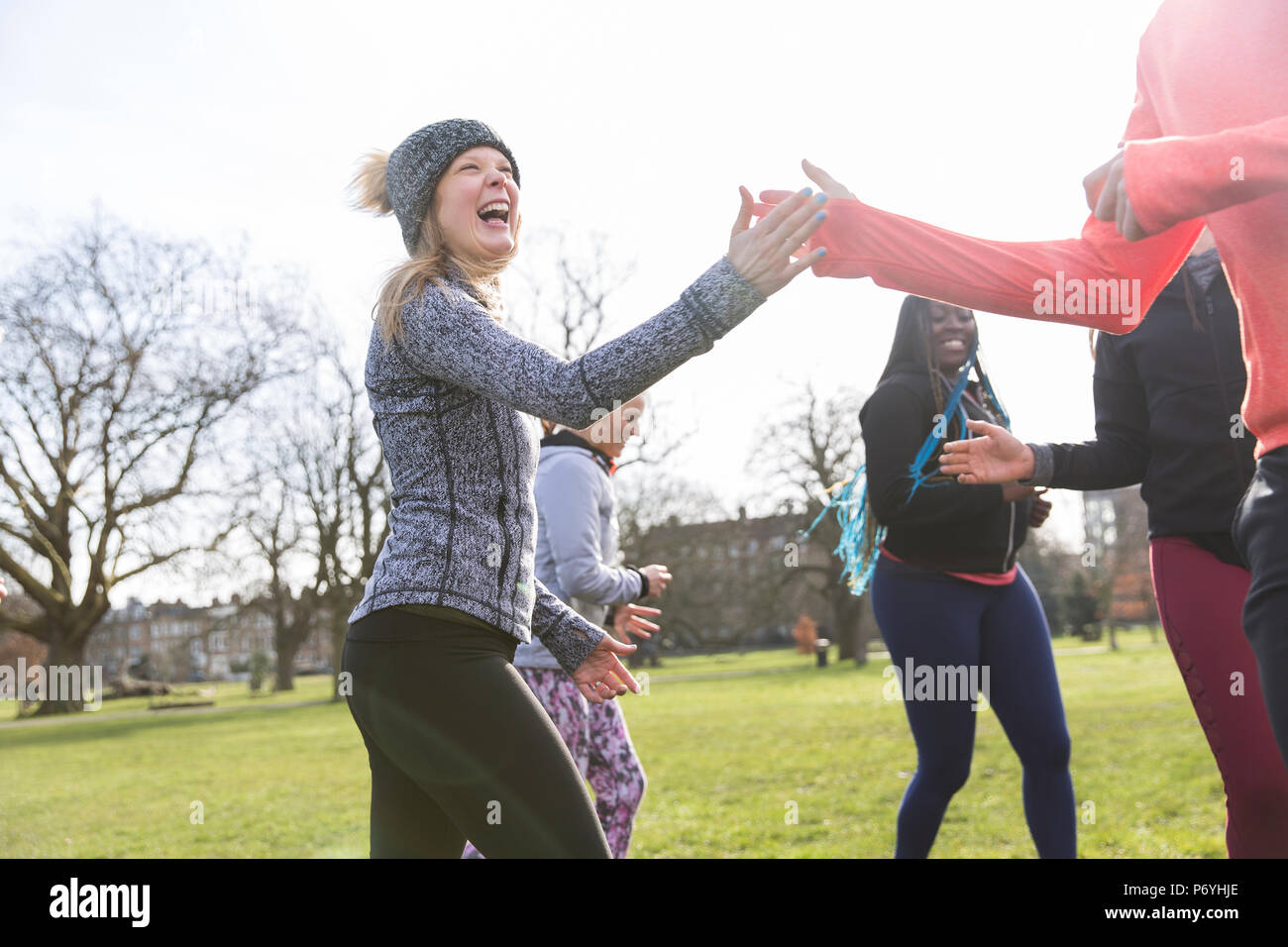Donna entusiasta di alta fiving classmate, esercitando nel soleggiato parco Foto Stock