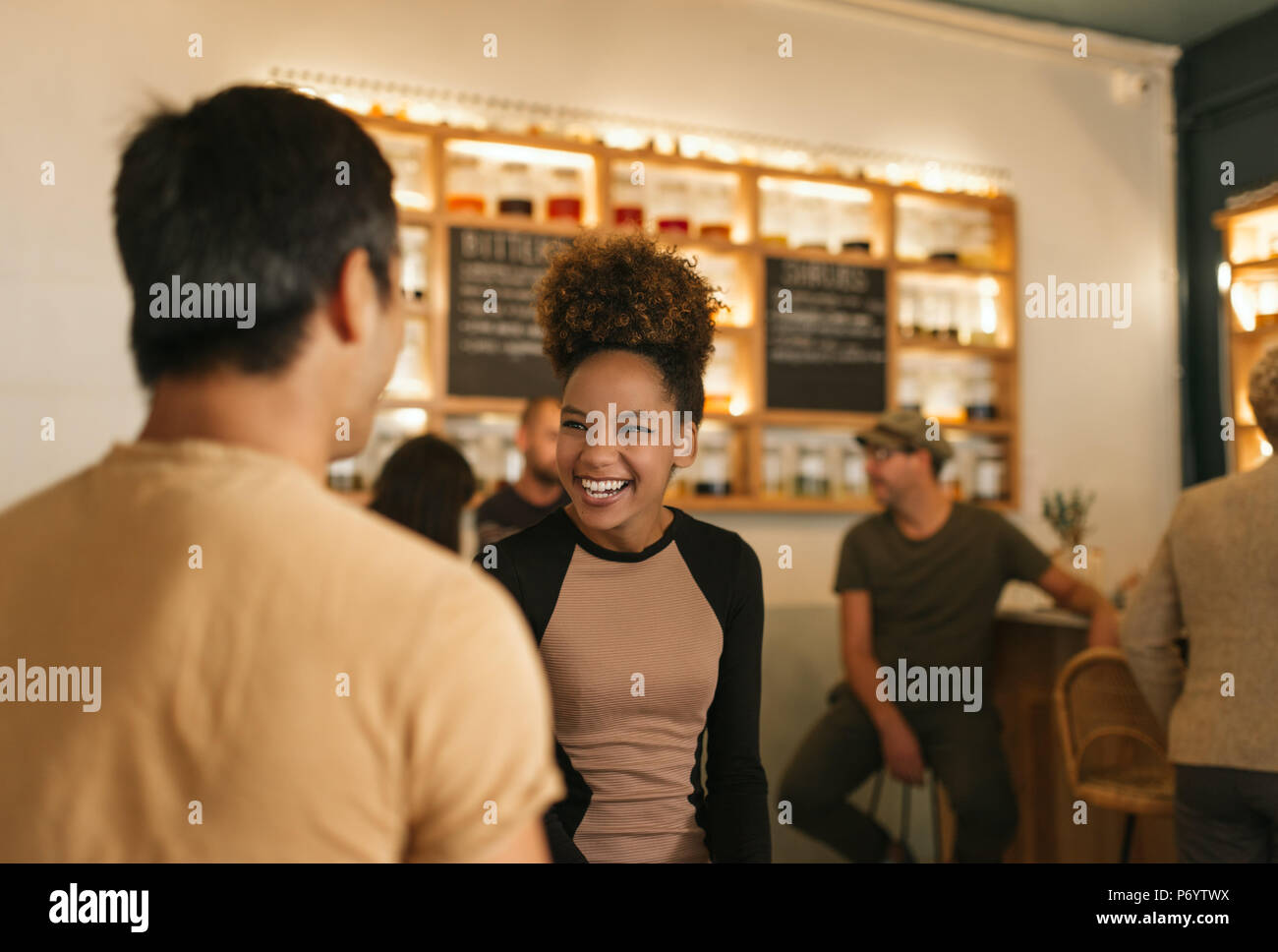 Ridendo giovane donna che parla con il suo amico in un bar Foto Stock