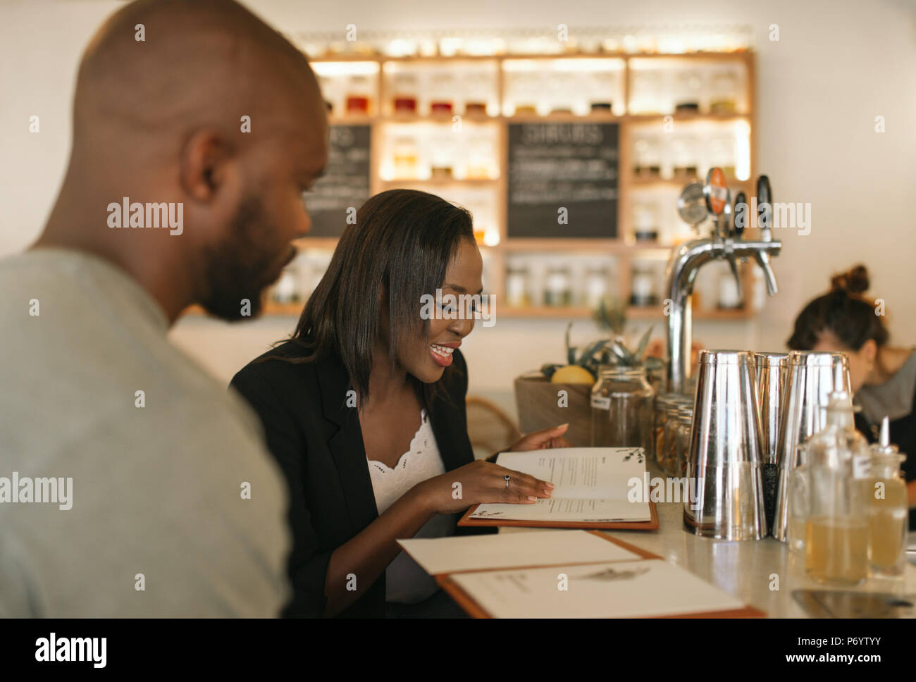 Sorridente giovane americano africano giovane leggendo i menu in una barra Foto Stock