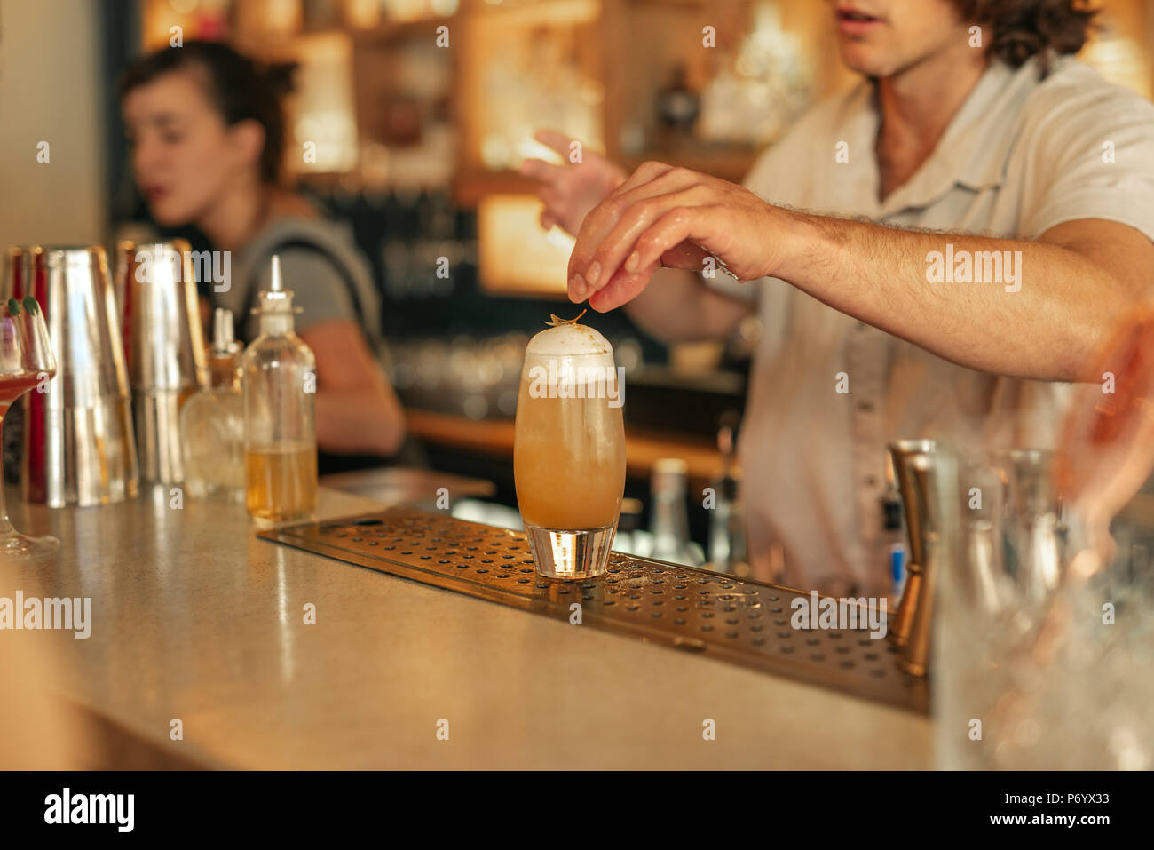 Barista rendendo cocktail dietro il bancone di un bar alla moda Foto Stock