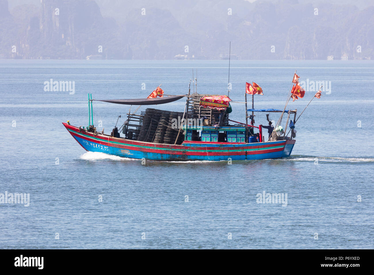 Colorate barche da pesca con le bandiere di Halong Bay, Quang Ninh provincia nordorientale, Vietnam, sud-est asiatico Foto Stock