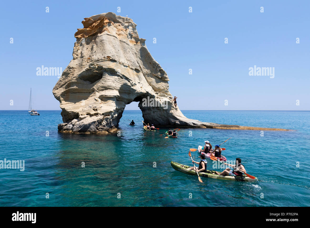 Kayakers andare attraverso arch rock formazione con acqua cristallina, Kleftiko, Milos, Cicladi, il Mare Egeo e le isole greche, Grecia, Europa Foto Stock