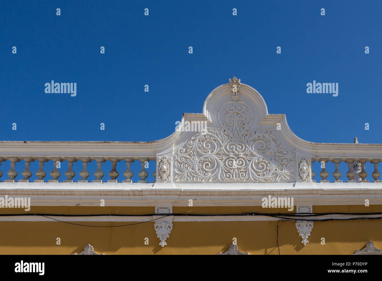 Colore bianco dell'ornamento di una recinzione di una casa portoghese con una facciata di colore giallo. Azzurro cielo. Castro Marim, Algarve, Portogallo. Foto Stock