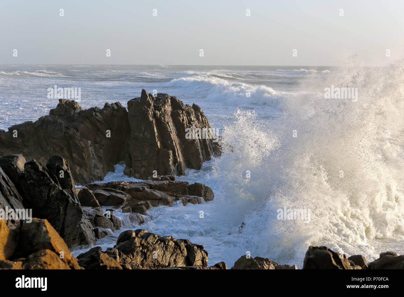 Tempesta di mare al tramonto con grandi onde contro la scogliera Foto Stock