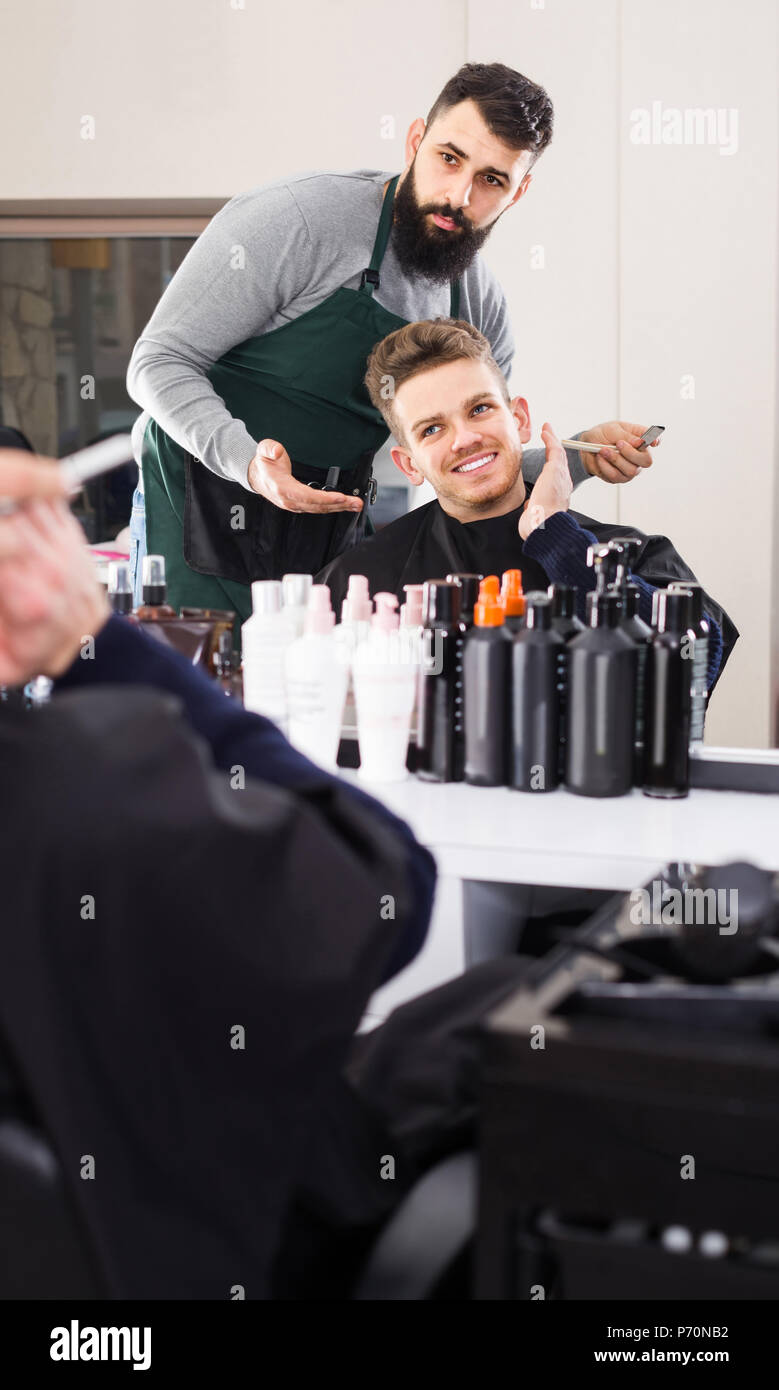 Giovane maschio spagnolo parrucchiere che mostra con conseguente scarto di  garanzia al cliente al parrucchiere Foto stock - Alamy