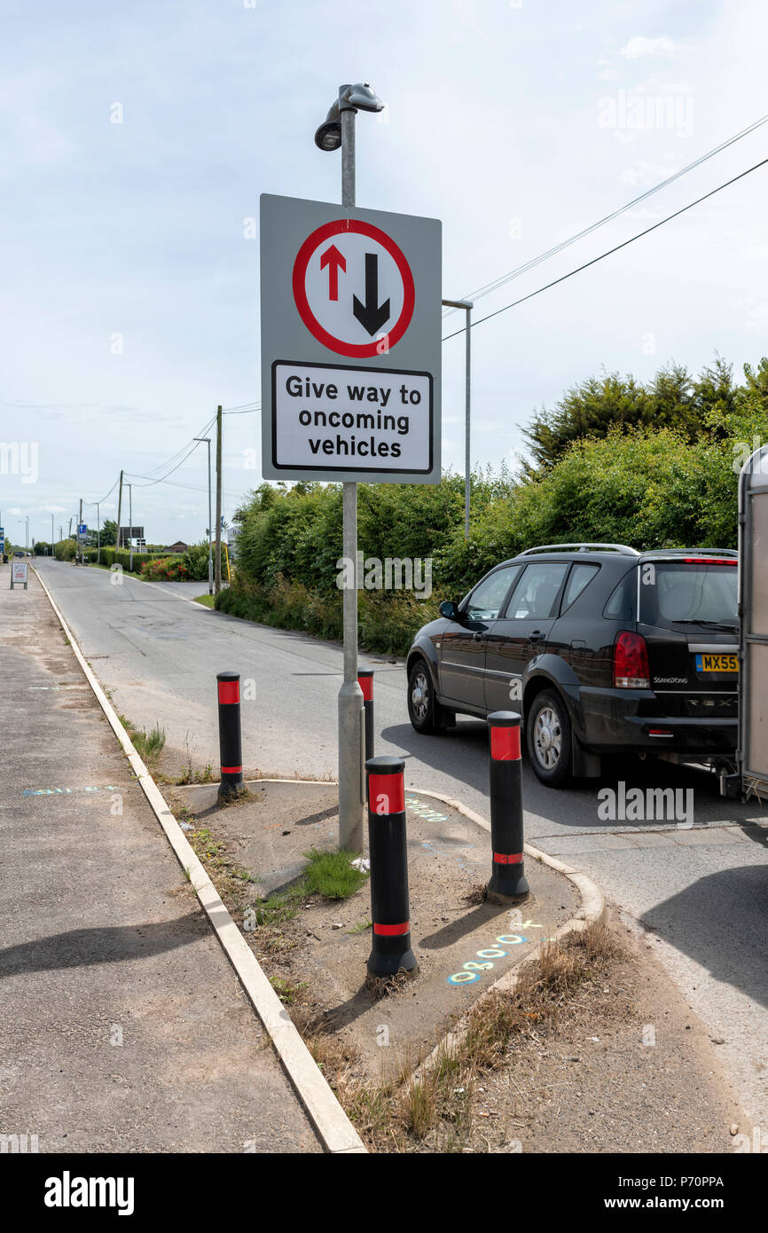 Auto passando un "dare modo ai veicoli che sopraggiungono' segno di Blackpool, Lancashire Foto Stock