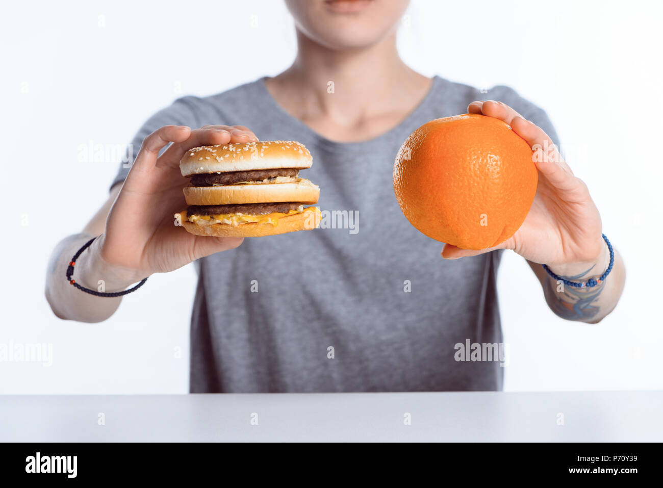 Ritagliato shot della ragazza con hamburger e arance mature Foto Stock