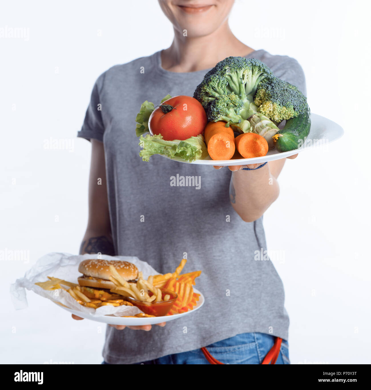 Ritagliato colpo di donna piastre di contenimento con verdure e cibo spazzatura Foto Stock