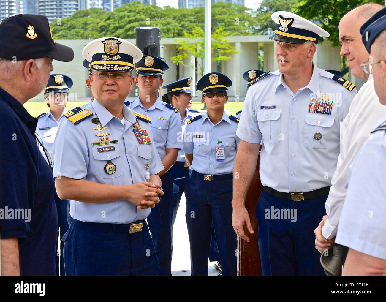 Officer responsabile Commodore Joel Garcia, Philippine Coast Guard, Lt. La Cmdr, Jeremy Obenchain ,U.S. Guardia costiera, consulente marittimo di difesa per la riduzione della minaccia e dell'agenzia U.S. Ambasciata, e Chief Petty Officer John O'Neil, U.S. Coast Guard Veterani di Guerra Associazione, discutere la vita del tenente James Crotty a livello militare Cimitero Americano, 9 maggio 2017. La cerimonia è stata culminata con il rivelare di Lt. Crotty il nome ormai inciso sull'U.S. La guardia costiera della parete nel cimitero. Foto Stock