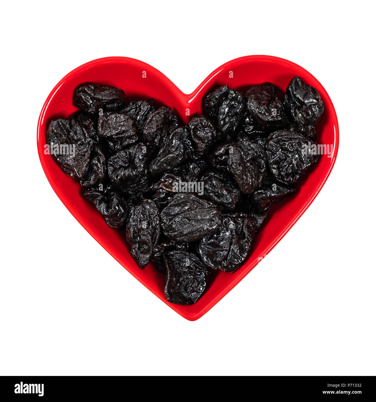Prugne secche prugne snocciolate e cuore in ciotola sagomata sullo sfondo Foto Stock