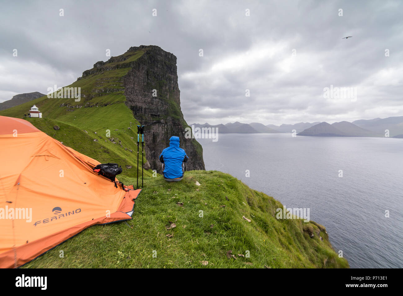 Escursionista e tenda sulle scogliere intorno Kallur faro, Kalsoy Isola, Isole Faerøer, Danimarca, Europa Foto Stock