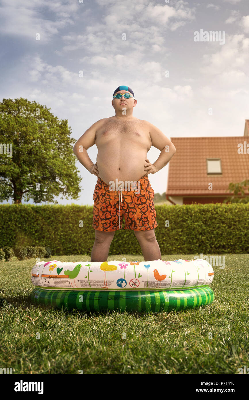Vacanze Economiche in casa, divertenti Uomo sovrappeso circa a nuotare nel cortile piscina Foto Stock