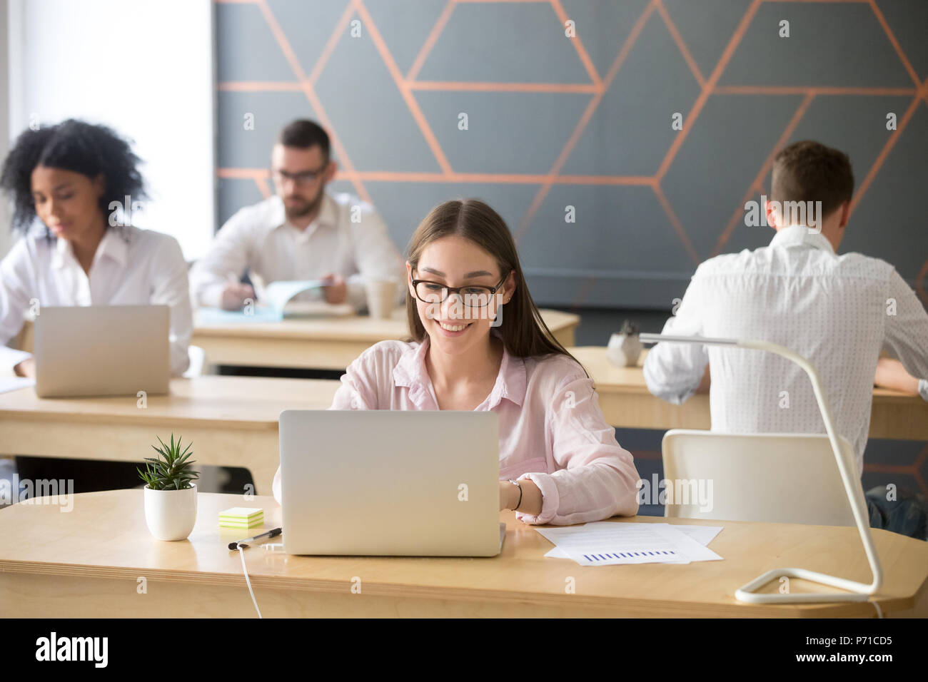 Felice dipendente occupato a lavorare al computer portatile in coworking space Foto Stock