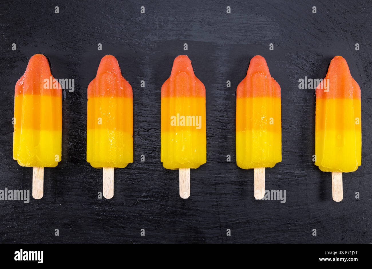 Gelato di frutta su stick su nero ardesia bordo. Focus su Popsicles. Foto Stock