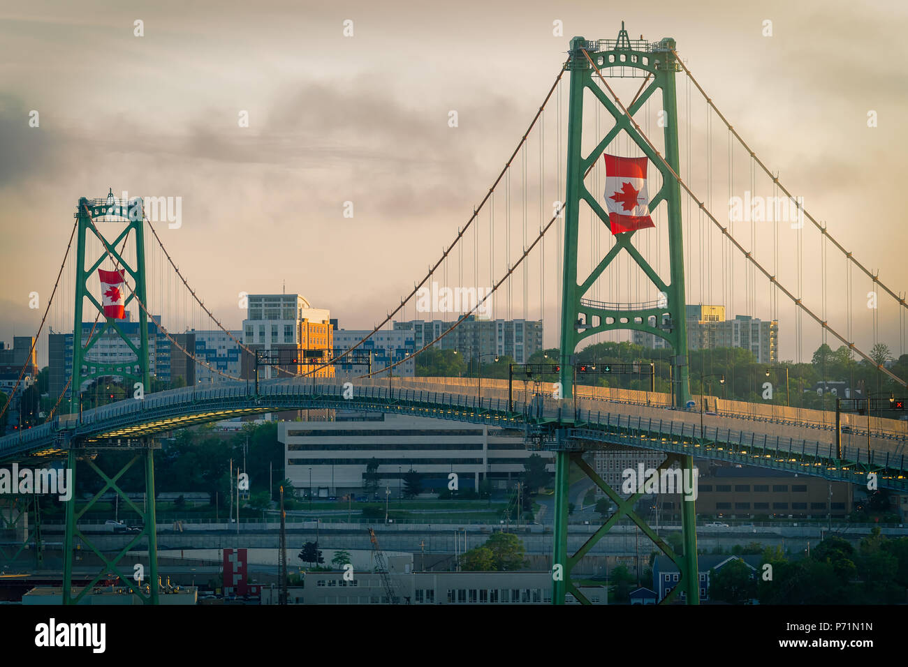 L'Angus L MacDonald Bridge al tramonto sul Canada il giorno con grandi bandiere canadesi battenti. Foto Stock