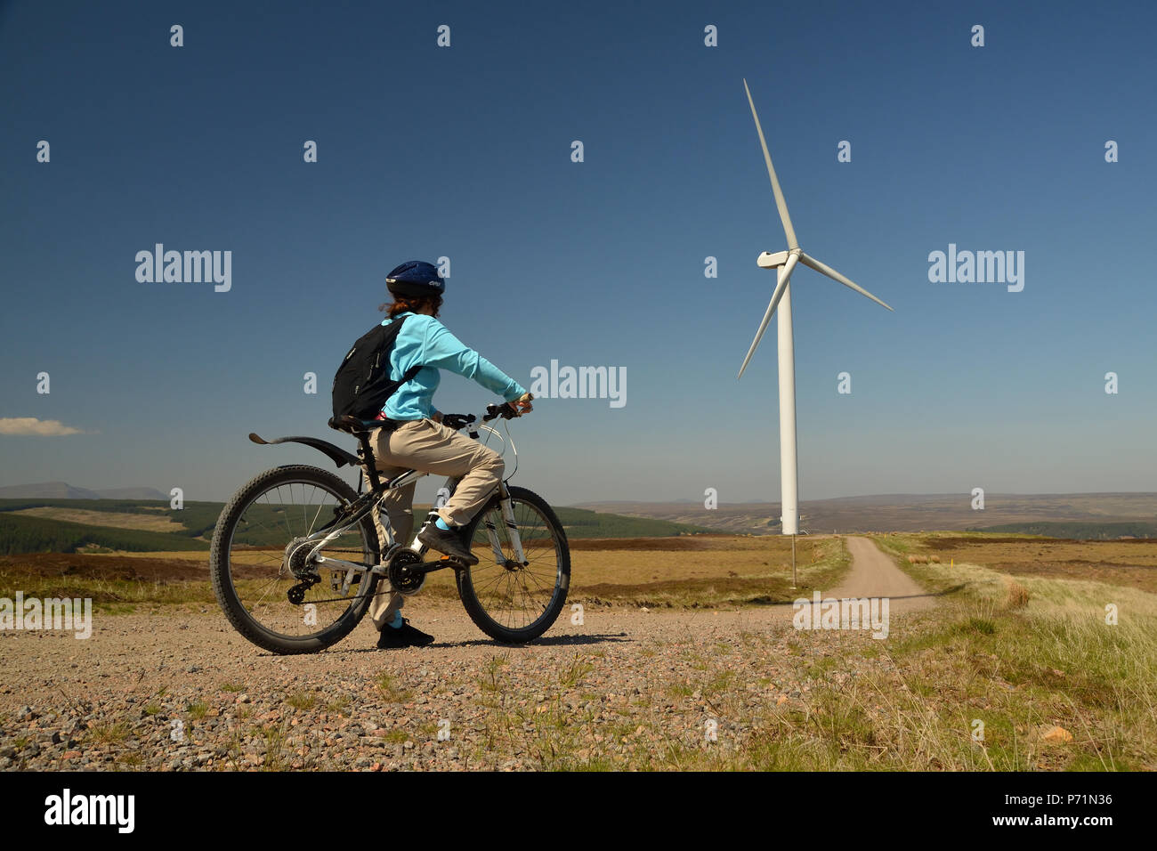 Un ciclista godendo la vista da una traccia in una fattoria eolica nelle Highlands Scozzesi. Foto Stock