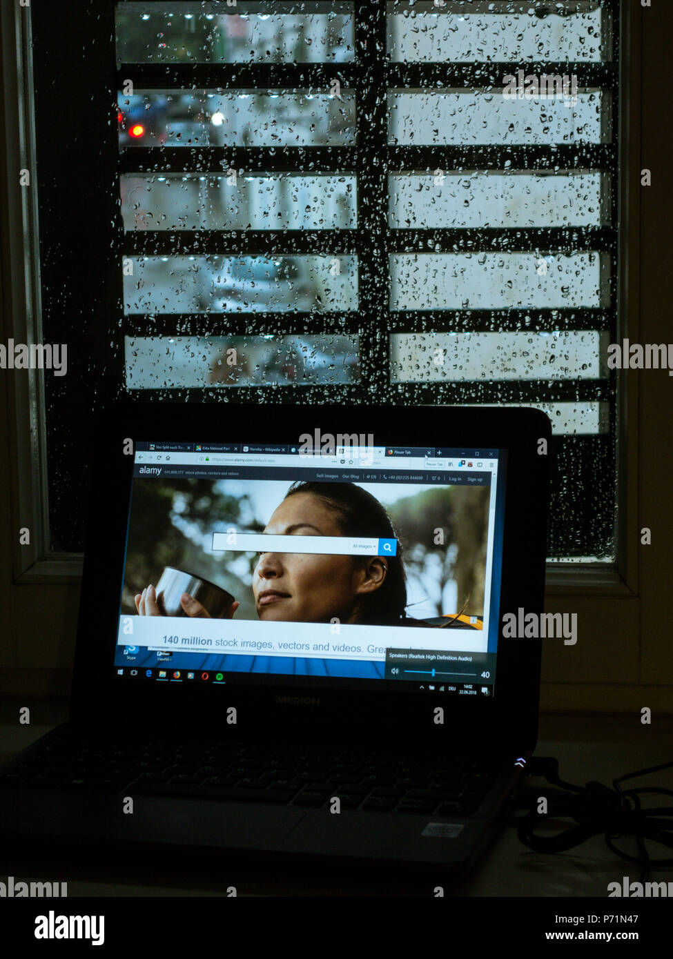 Sullo schermo del computer di fronte a una finestra colorate dalle gocce di pioggia Foto Stock