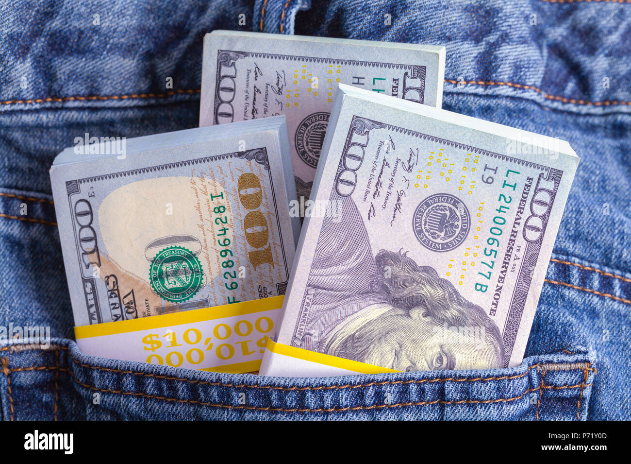Jeans blu farcite con pile di denaro contante. Foto Stock