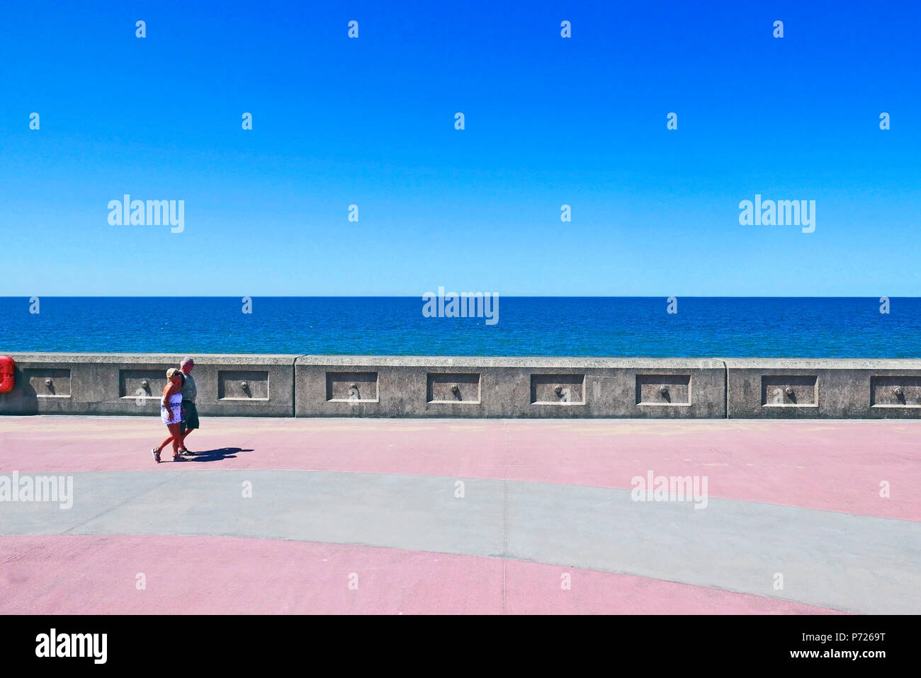 Coppia di mezza età in estate casual wear camminando lungo il lungomare di Blackpool in una calda giornata di sole Foto Stock