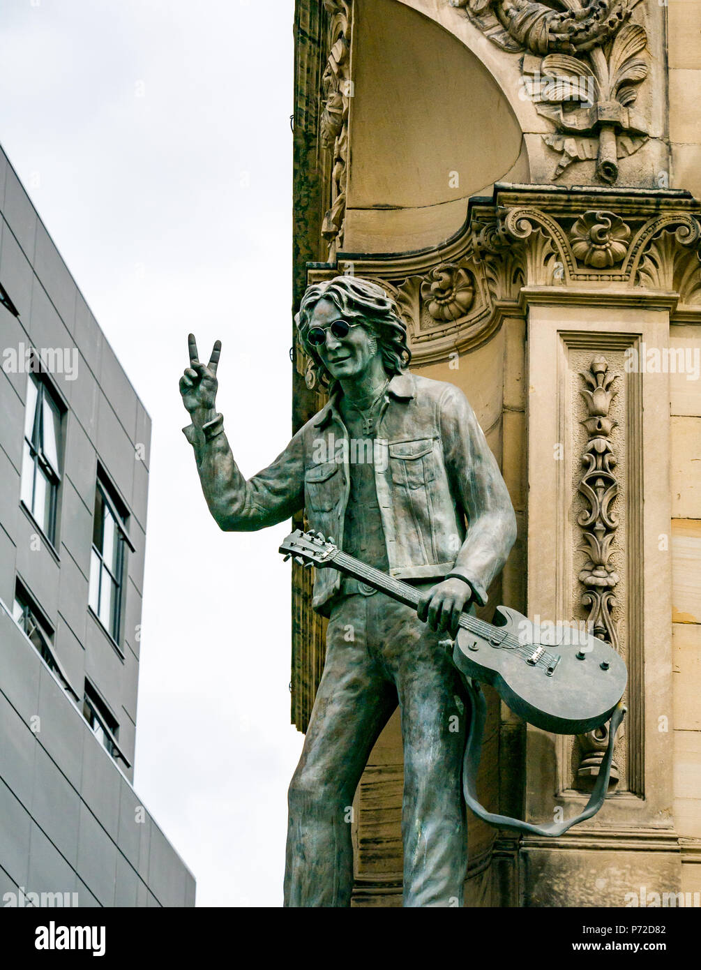 Statua di John Lennon tenendo la chitarra e dando V segno, dura giornata di notte Hotel, N John Street, Liverpool, England, Regno Unito Foto Stock