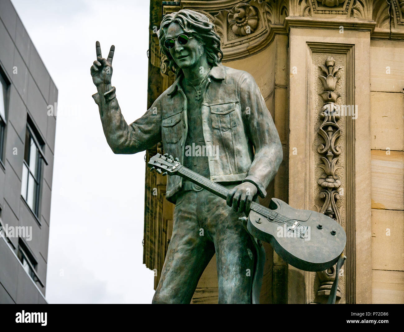 Statua di John Lennon tenendo la chitarra e dando V segno, dura giornata di notte Hotel, N John Street, Liverpool, England, Regno Unito Foto Stock