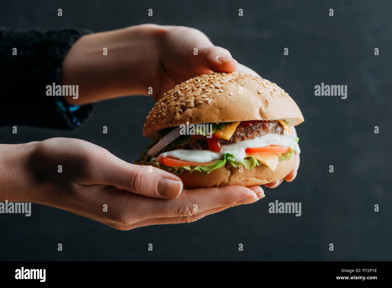 Vista ritagliata della mani femminili con americana tradizionale hamburger fatti in casa Foto Stock