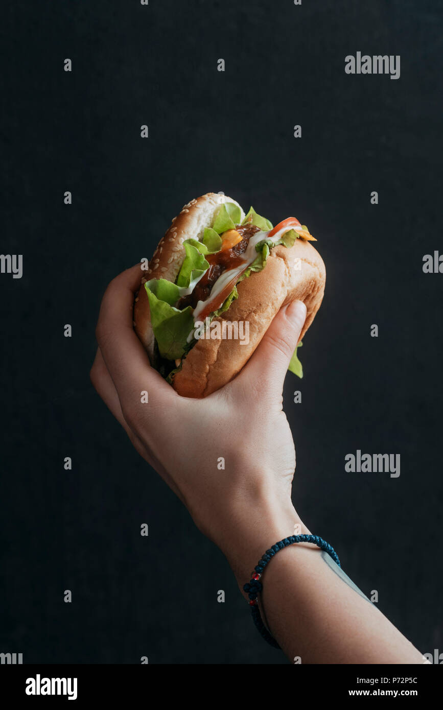 Vista ritagliata della persona holdong gustoso cheeseburger Foto Stock