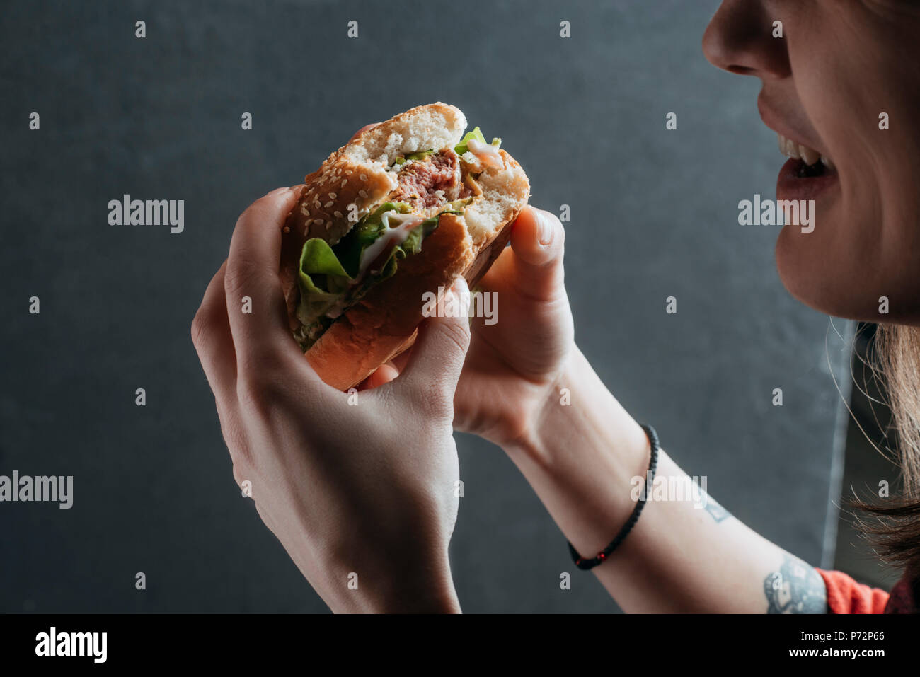 Vista ritagliata della donna mangiare hamburger gustoso Foto Stock