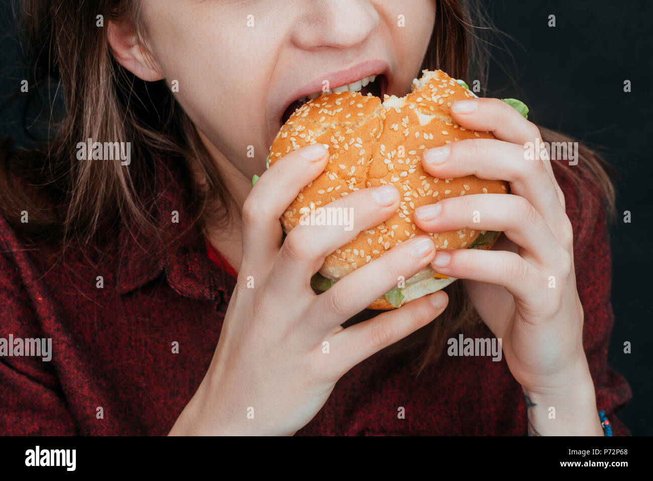 Vista ritagliata della ragazza di mordere gustoso hamburger Foto Stock