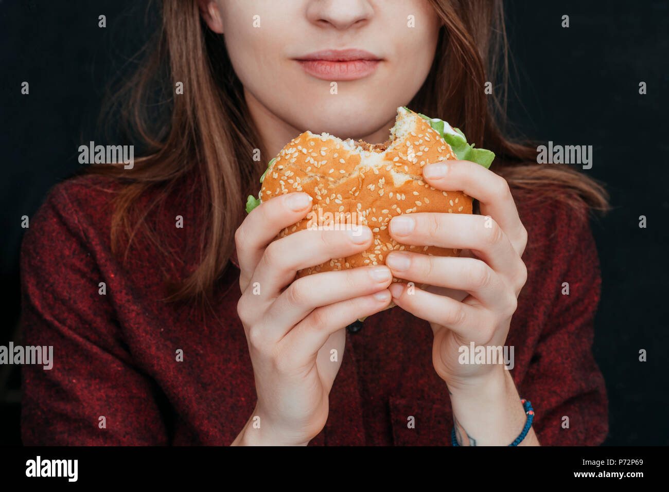 Vista ritagliata della ragazza di mangiare saporito cheeseburger Foto Stock