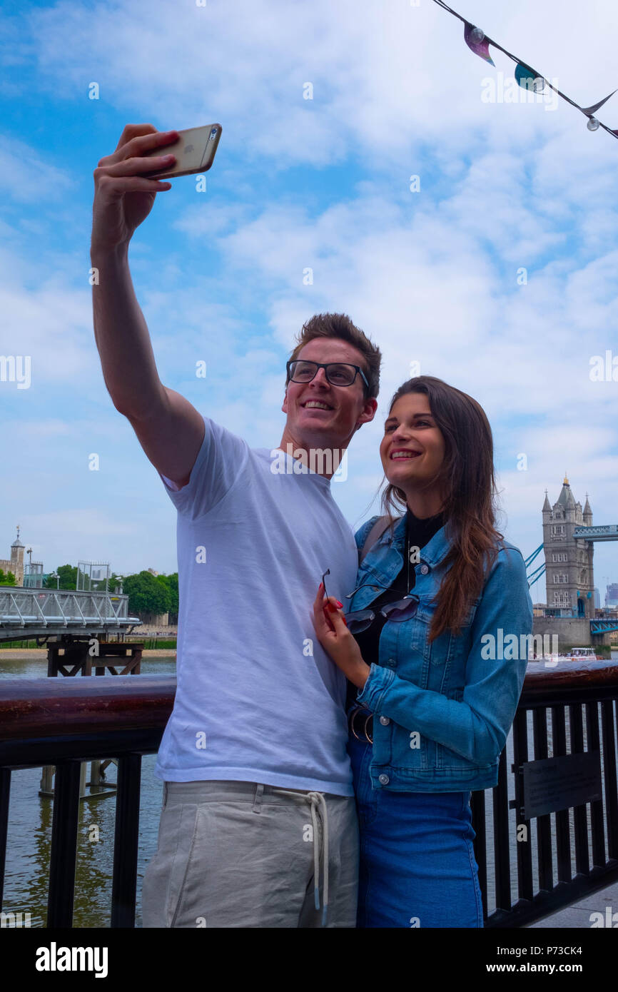 Londra, Inghilterra. 4 luglio 2018. Una coppia in vacanza dalla loro casa in Belgio prendete un selfie vicino il Tower Bridge di Londra su un'altra giornata molto calda. La presente ondata di caldo è impostata per continuare. ©Tim anello/Alamy Live News Foto Stock