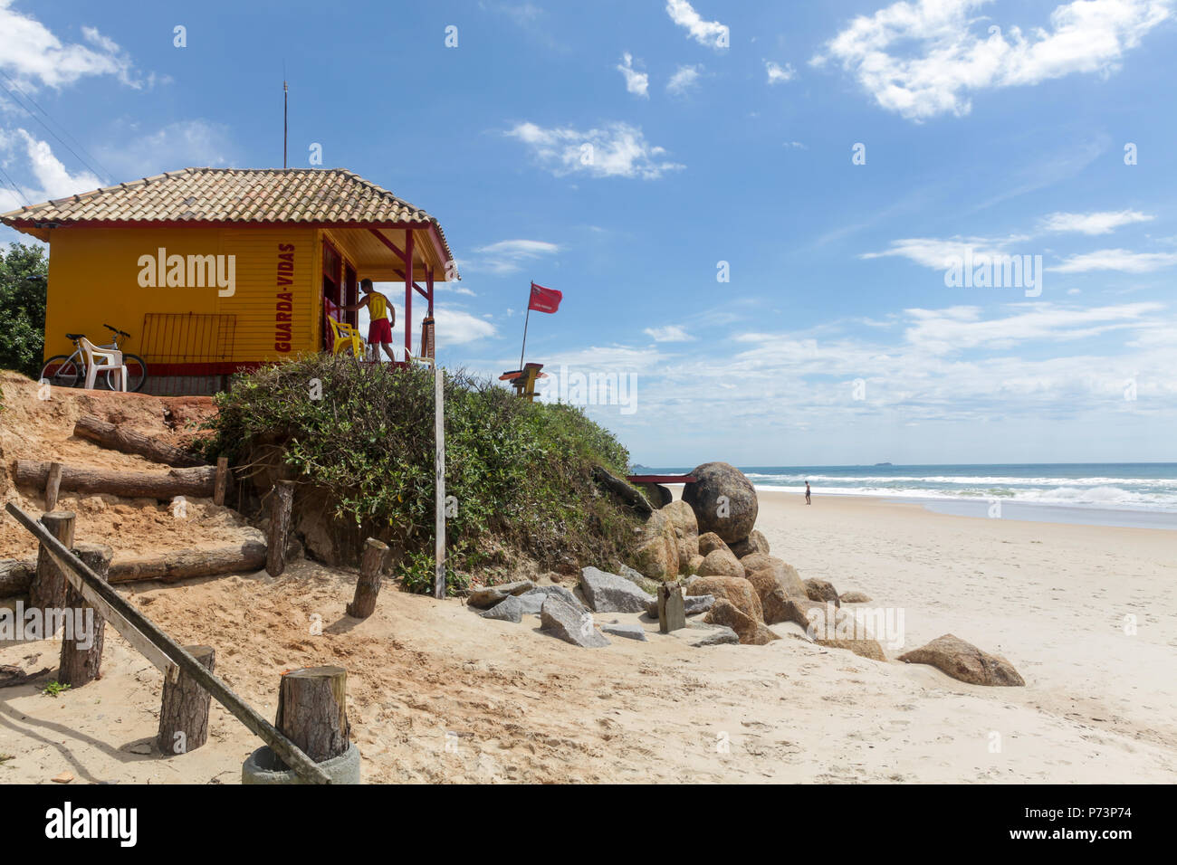 Florianopolis, Santa Catarina, Brasile. Bagnino riposare sulla spiaggia con bandiera rossa, indicando un pericoloso mare sulla soleggiata giornata estiva. Foto Stock