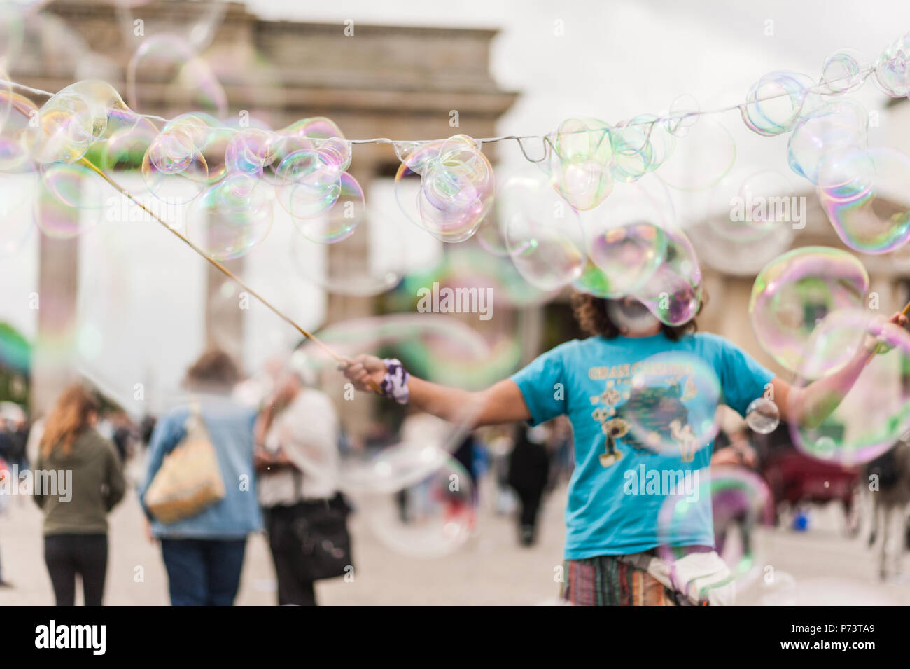 Colorate bolle di sapone galleggianti in primo piano. Street performer, busker, divertente la folla davanti alla Porta di Brandeburgo a Berlino. Foto Stock
