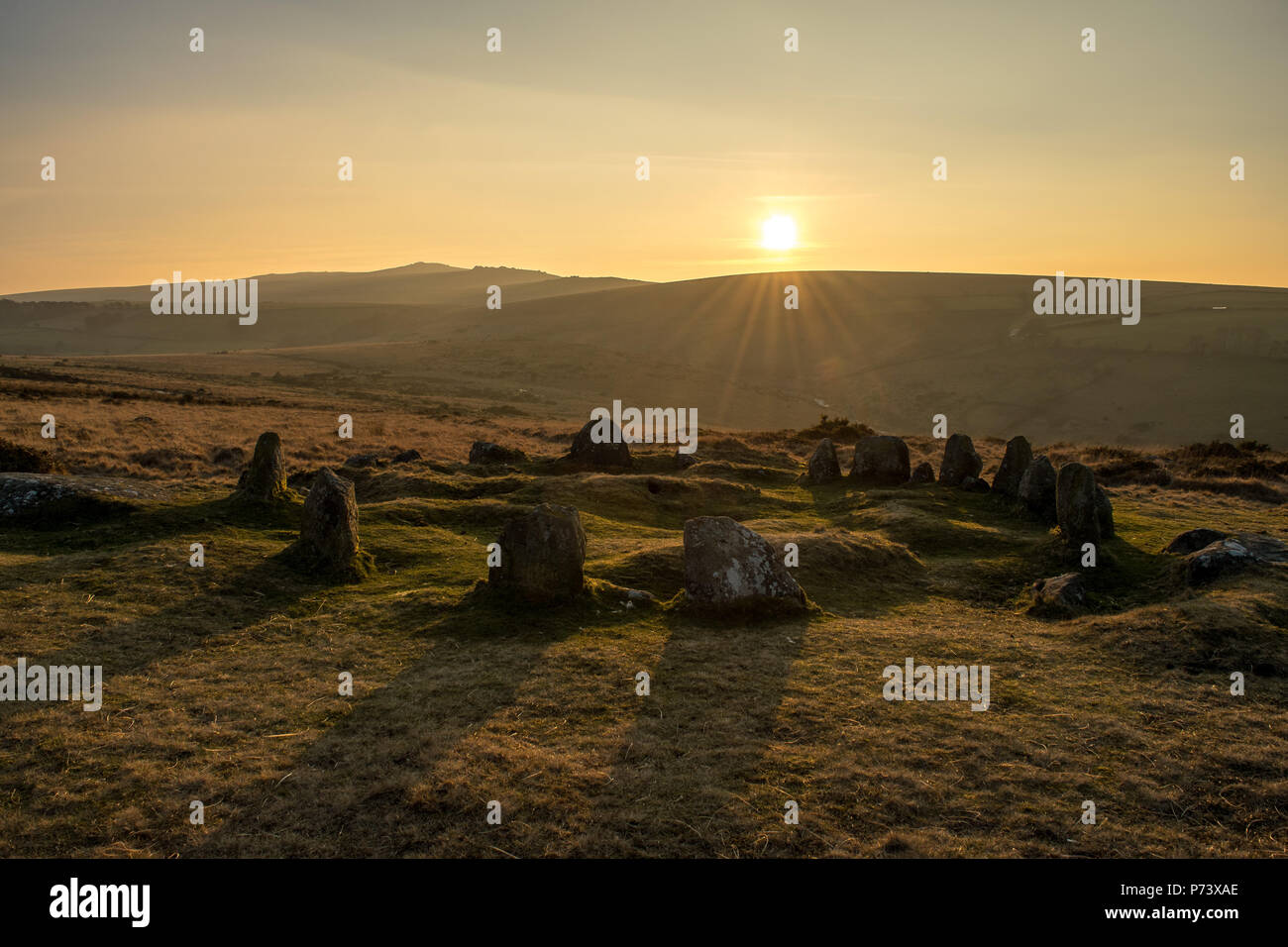 Luce dorata attraverso le antiche granito noto come le nove fanciulle cerchio di pietra sul Dartmoor Foto Stock