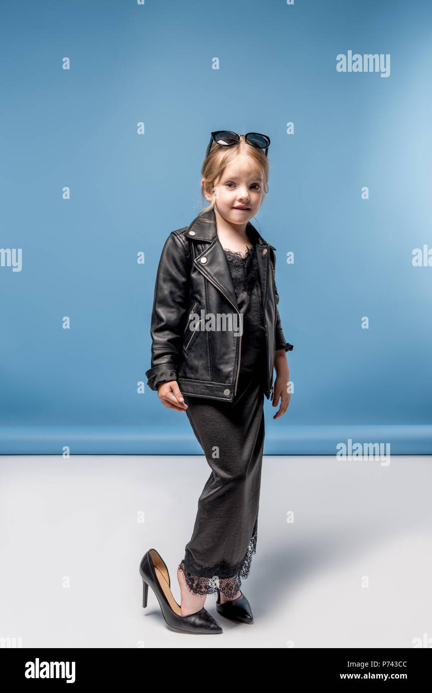 Elegante adorabile bambina indossa grandi tacchi, vestito nero e giacca di  pelle mentre guardando la fotocamera Foto stock - Alamy