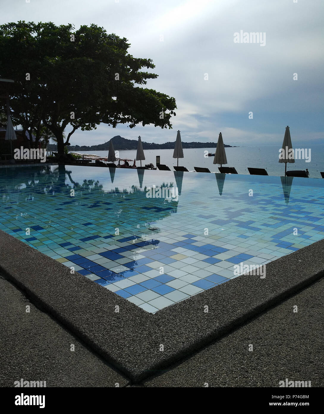 Piscina sulla spiaggia con ombrelloni piegato Foto Stock