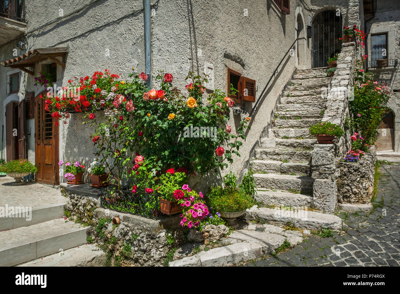 Vicoli e scalinate in pietra dell'antico borgo di Opi. L'angolo della casa decorata con fiori e vasi colorati. Abruzzo Foto Stock