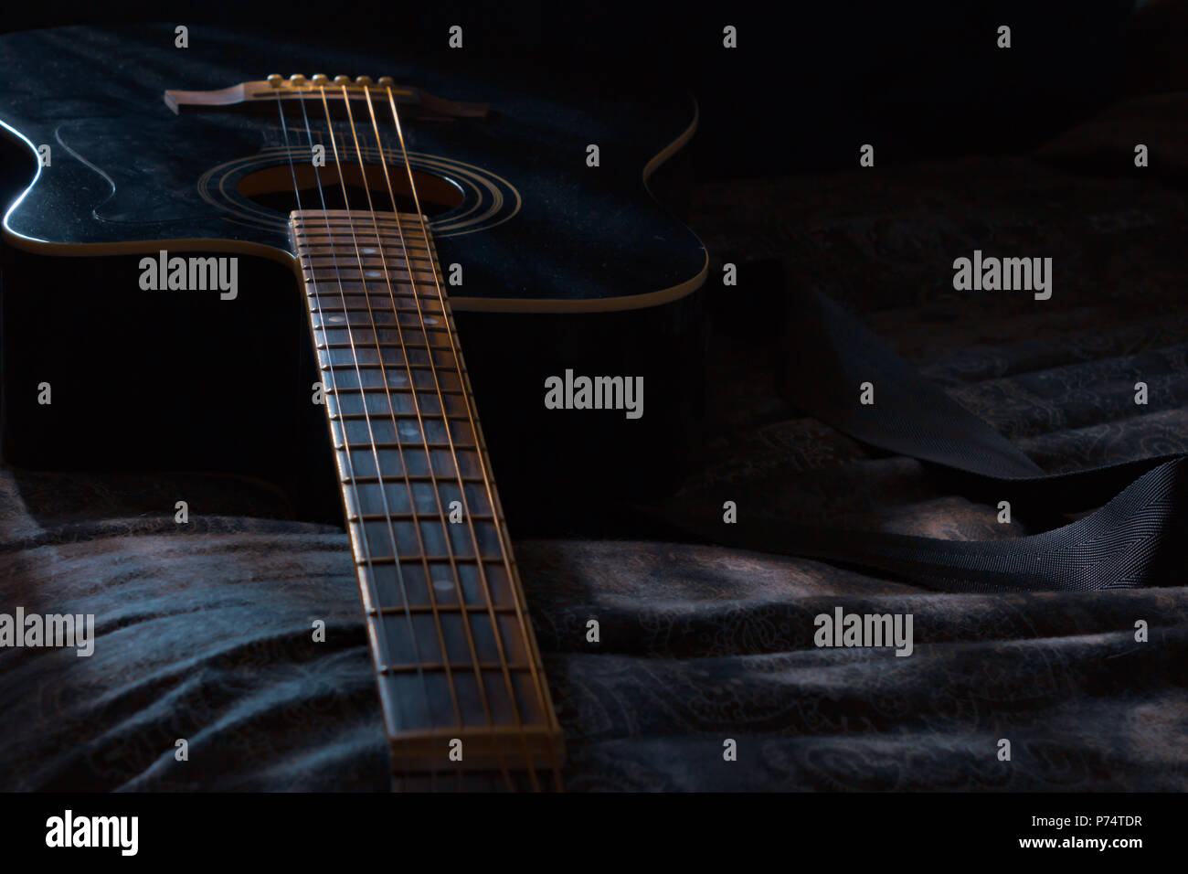 Posa di chitarra in camera oscura con il chiaro di luna brilla su di esso Foto Stock