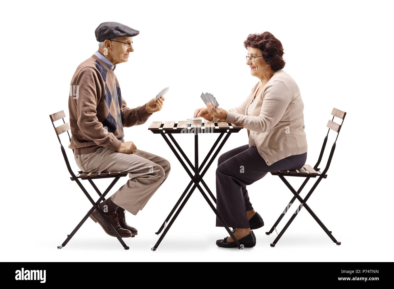 Gli anziani seduti ad un tavolo e giocare a carte isolati su sfondo bianco Foto Stock