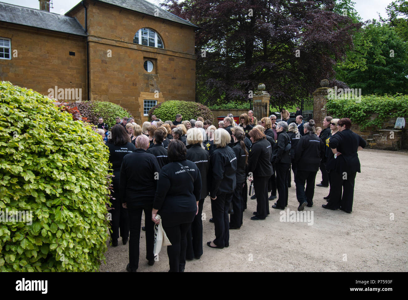Rock Choir Althorp House Northampton canta canzoni all'esterno delle signore in attesa di cantare le persone cori di persona edificio in pietra storia di cespuglio femminile storico Foto Stock