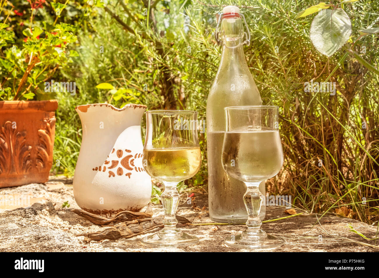 Coprire di nuovo normale vino da tavola con rustici brocca e bottiglia di acqua minerale, servita nel sud italia. I bicchieri sono riempiti con vino bianco e acqua. Foto Stock