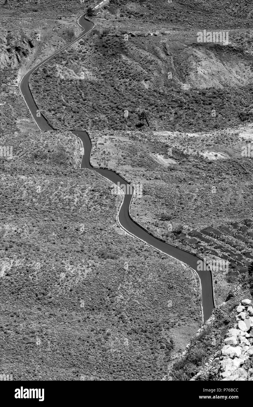 Lanzarote isole Canarie Spagna, elevati vista orizzontale della pittoresca curva country road andando diagonalmente attraverso terra deserta, immagine in bianco e nero Foto Stock