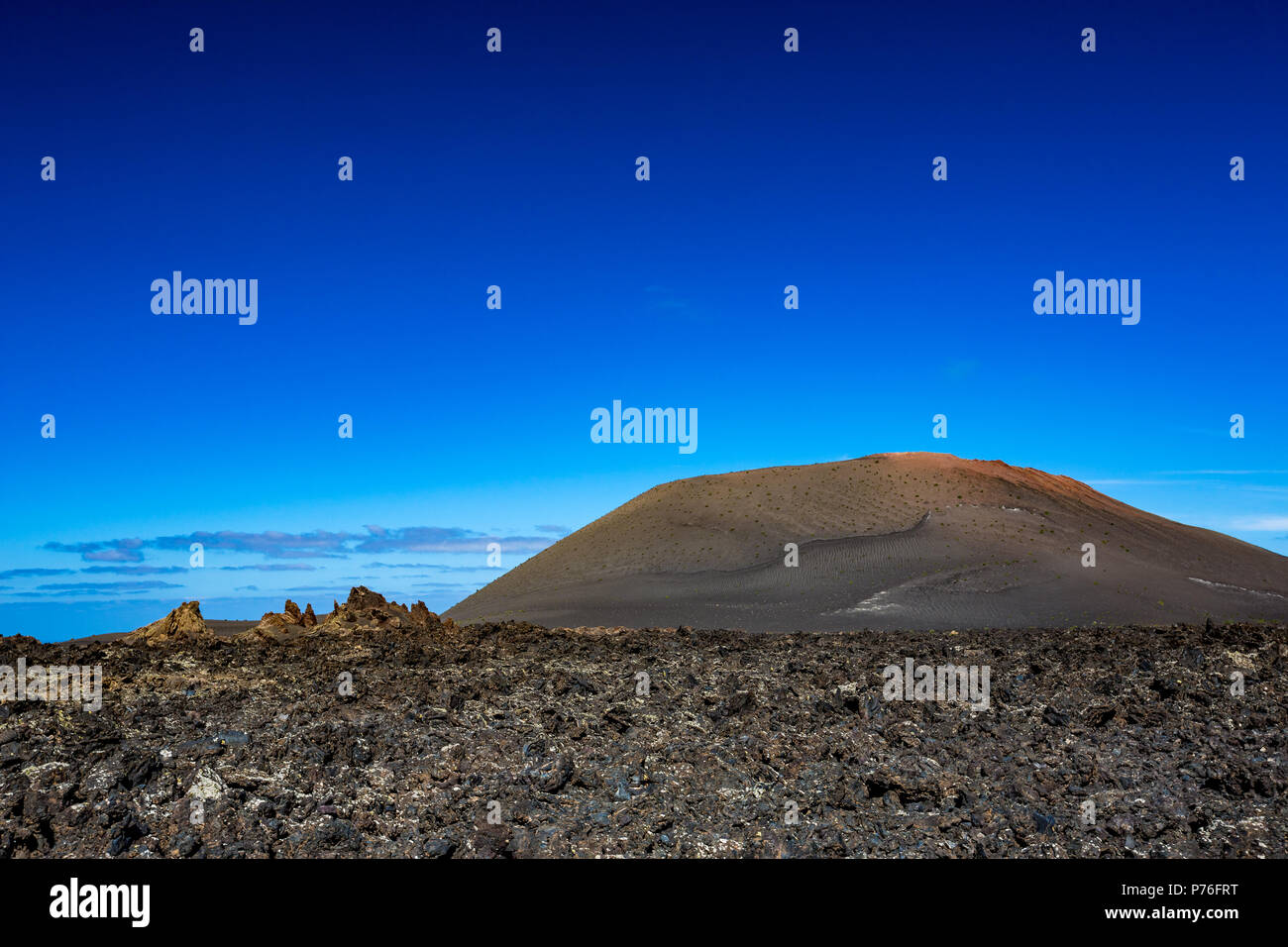 Il vasto vuoto e la solitudine di Lanzarote nero lava congelato deserto vulcanico e uno eroso collina marrone in background Foto Stock