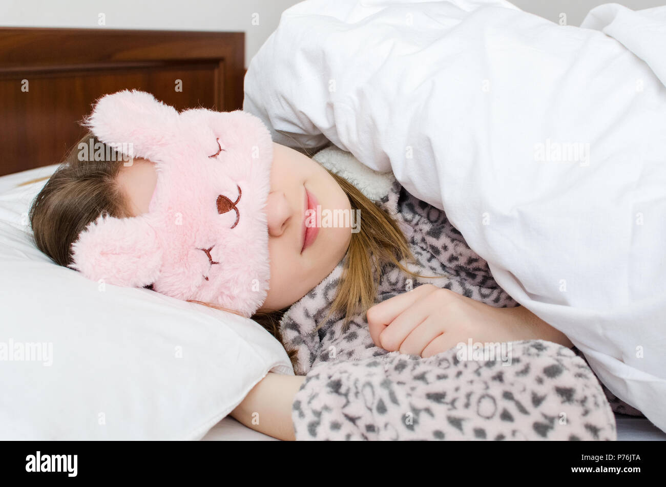 Bella giovane donna nella cute maschera di sonno e caldo pigiama sdraiato  sul letto e dormire al mattino Foto stock - Alamy